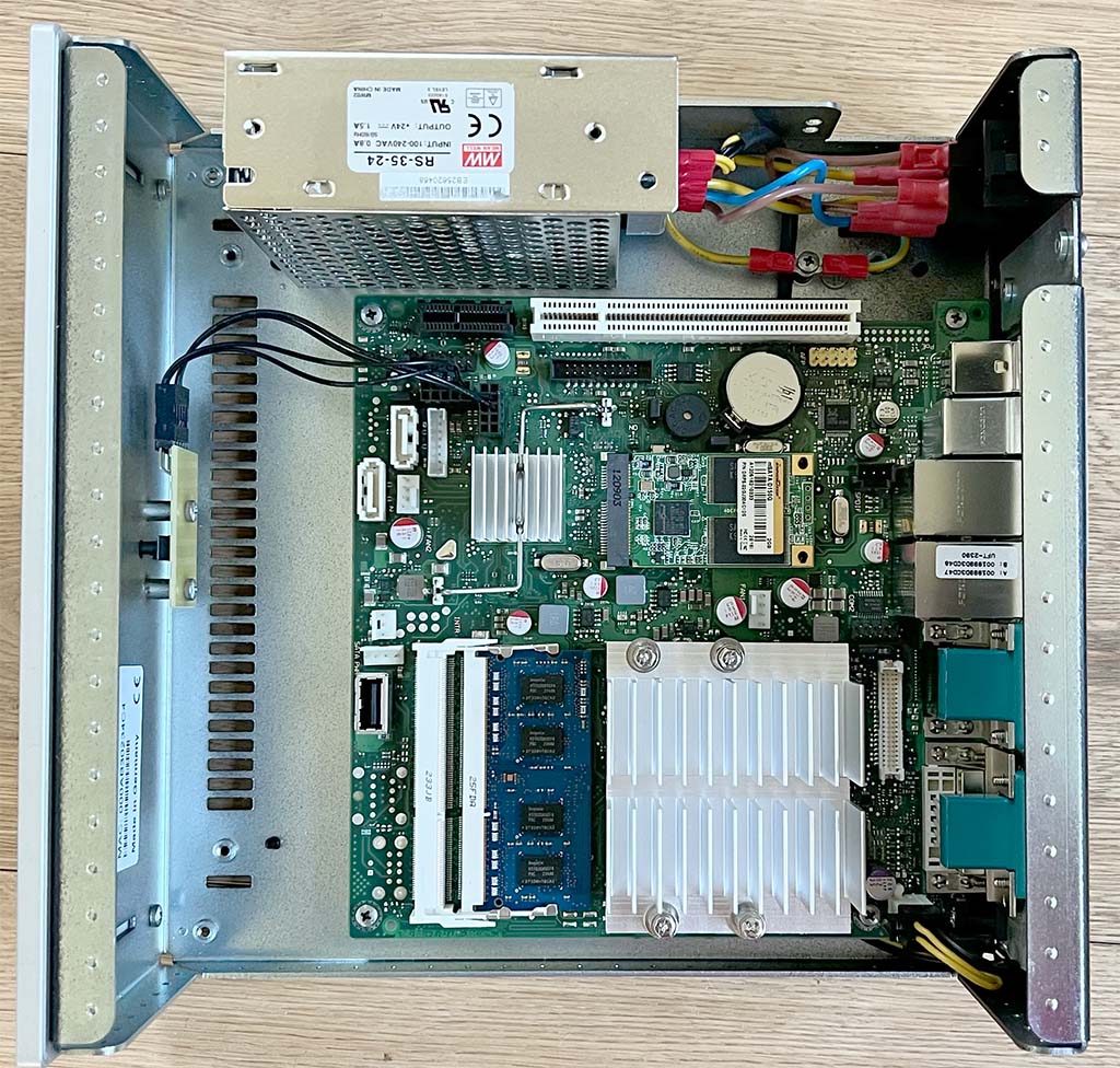 Geöffneter Gira Homeserver 4: Auf der Hauptplatine/Motherboard mit passivem CPU-Kühler befinden sich das 2 GB Flash-Speicher-Modul, der 1 GB große SO-DIMM Arbeitsspeicher und die Anschlüsse für die Backplane. Das Netzteil befindet sich mit im Gehäuse.